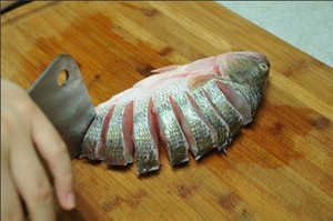 將鱸魚清洗干凈，從脊椎處切斷至腹部，腹部保留1cm左右不要切斷。