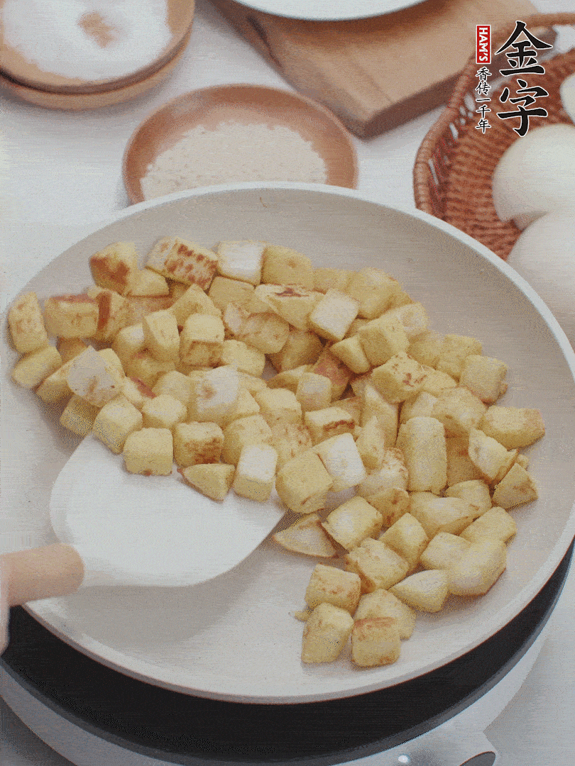 起鍋熱油，倒入饅頭丁，小火煎至蛋液凝固定型再翻面，饅頭丁部煎至金黃時(shí)盛起待用。