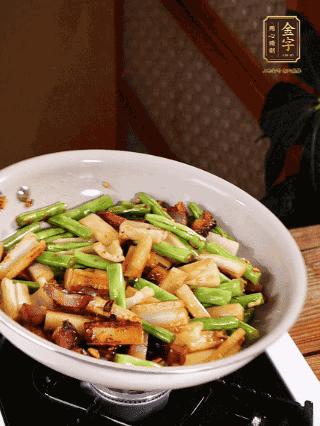 油熱下蒜末、干辣椒、醬肉煸炒出香味，依次下藕條、豆角翻炒均勻